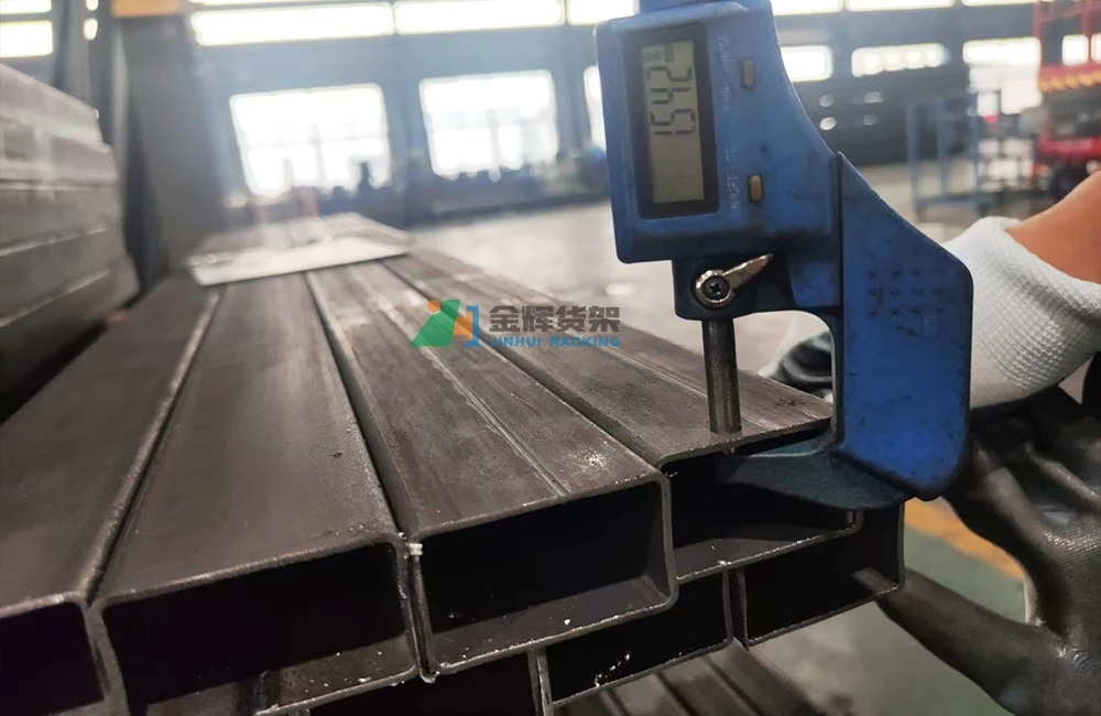 Quality inspector measuring racking component steel thickness with digital caliper
